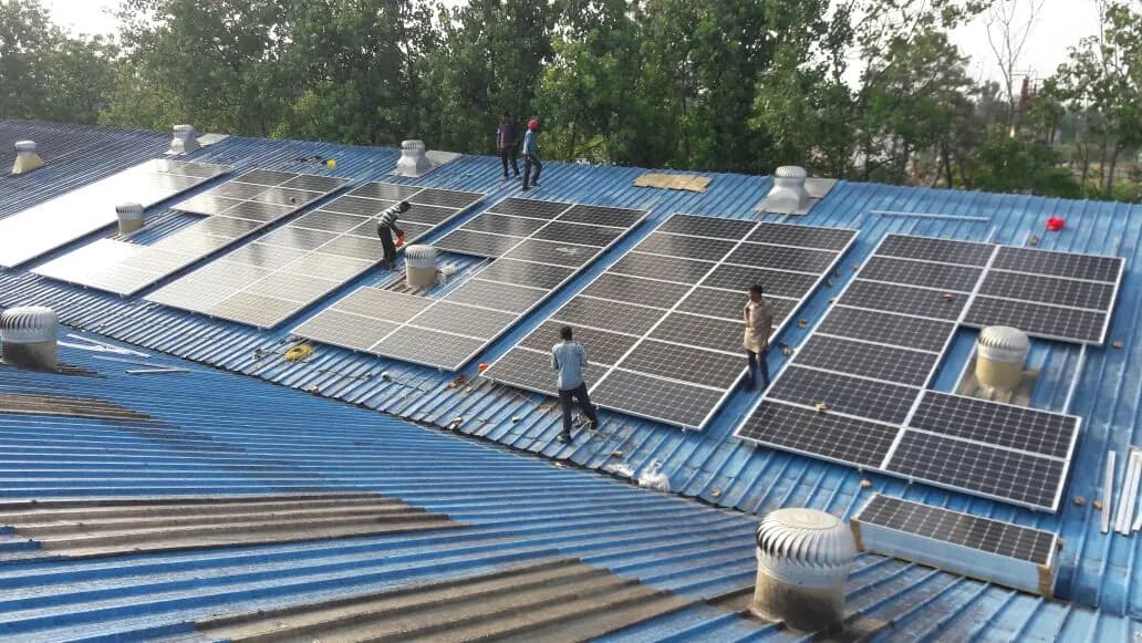 Solar modules being installed on the blue metal roof at Pernod Ricard, Dera Bassi